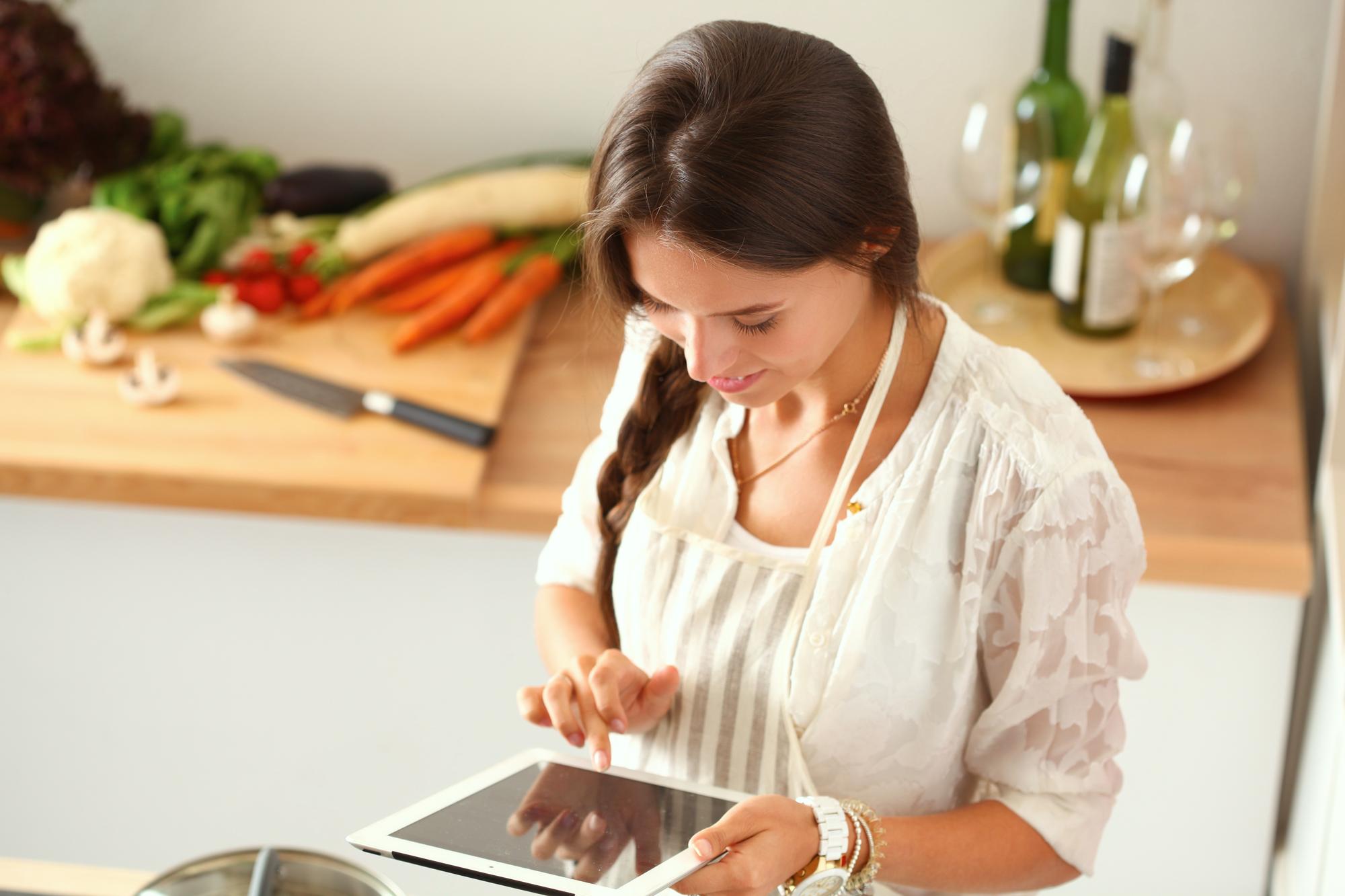 Instructor writing recipe notes on tablet in kitchen